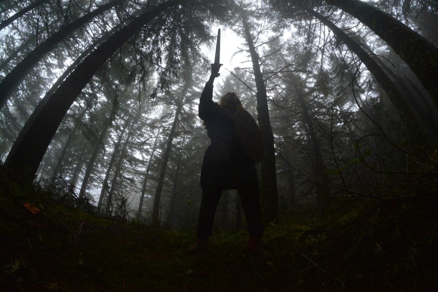 DOT Dominus raising a sword in a fog-bound pine forest